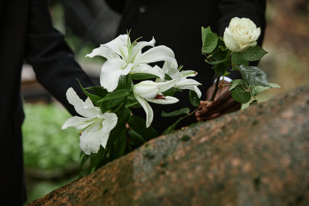 Flores brancas e lírios sendo colocados sobre sepultura em homenagem fúnebre