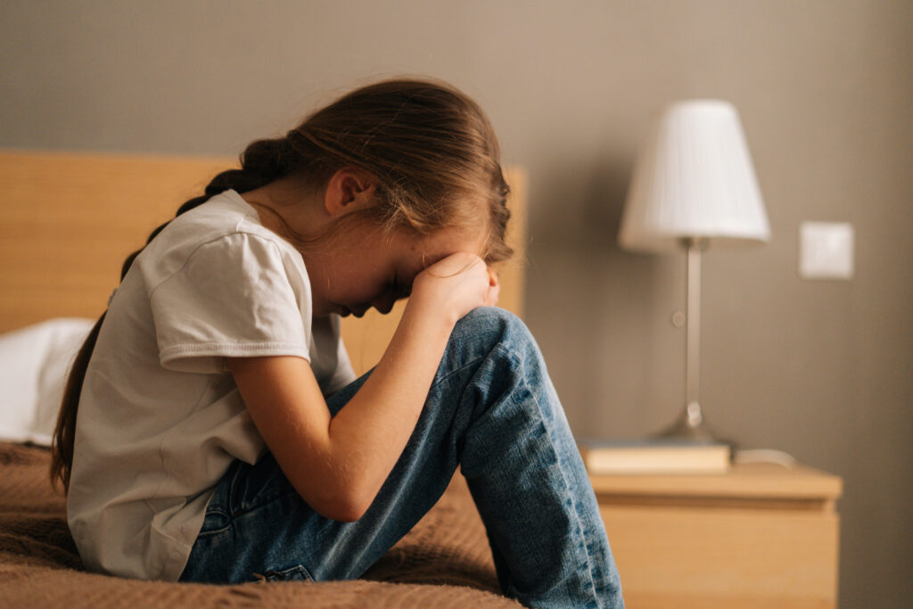 Criança com expressão triste e pensativa, representando os sentimentos que podem surgir durante o luto infantil.