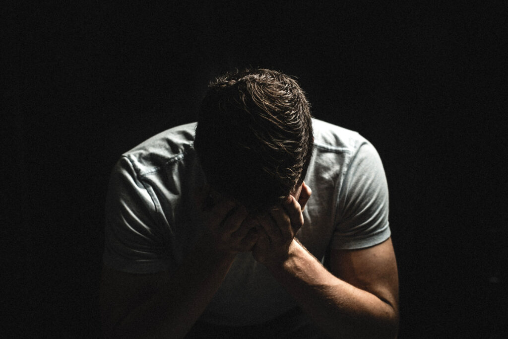 Homem com as mãos no rosto demonstrando tristeza